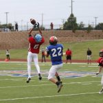 Red player jumping to catch football.